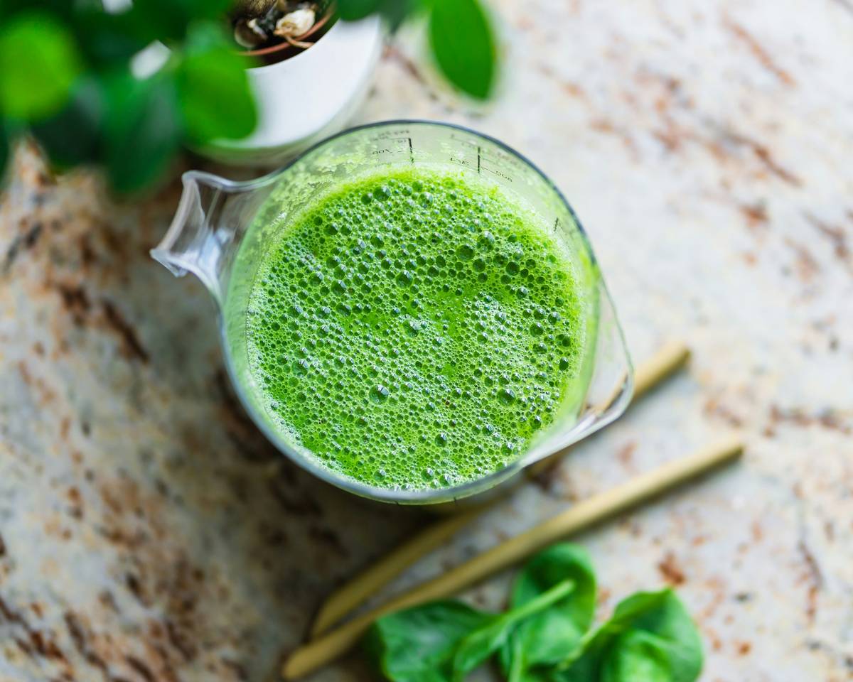 Woman blending a vibrant natural fruit smoothie enhancer with berries and greens