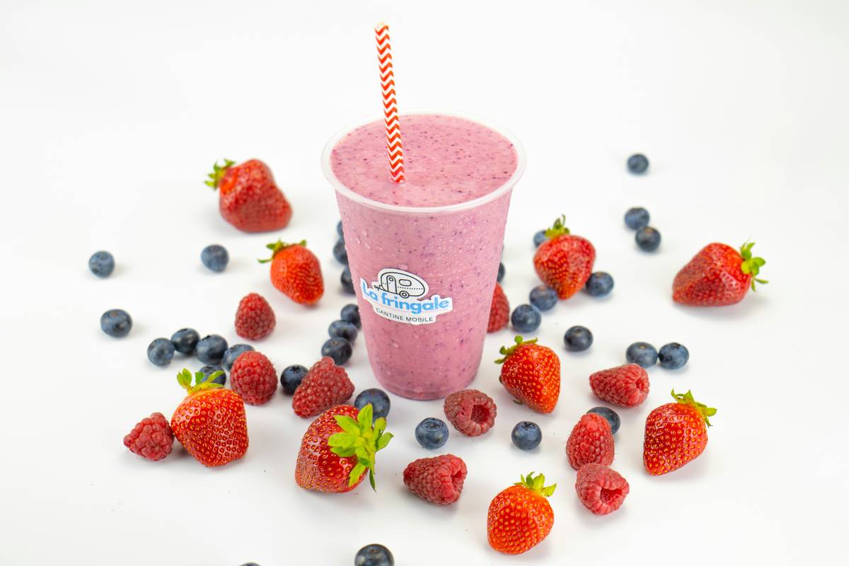 Natural post-workout smoothie in a mason jar with fresh berries, spinach, and almond milk beside workout gear
