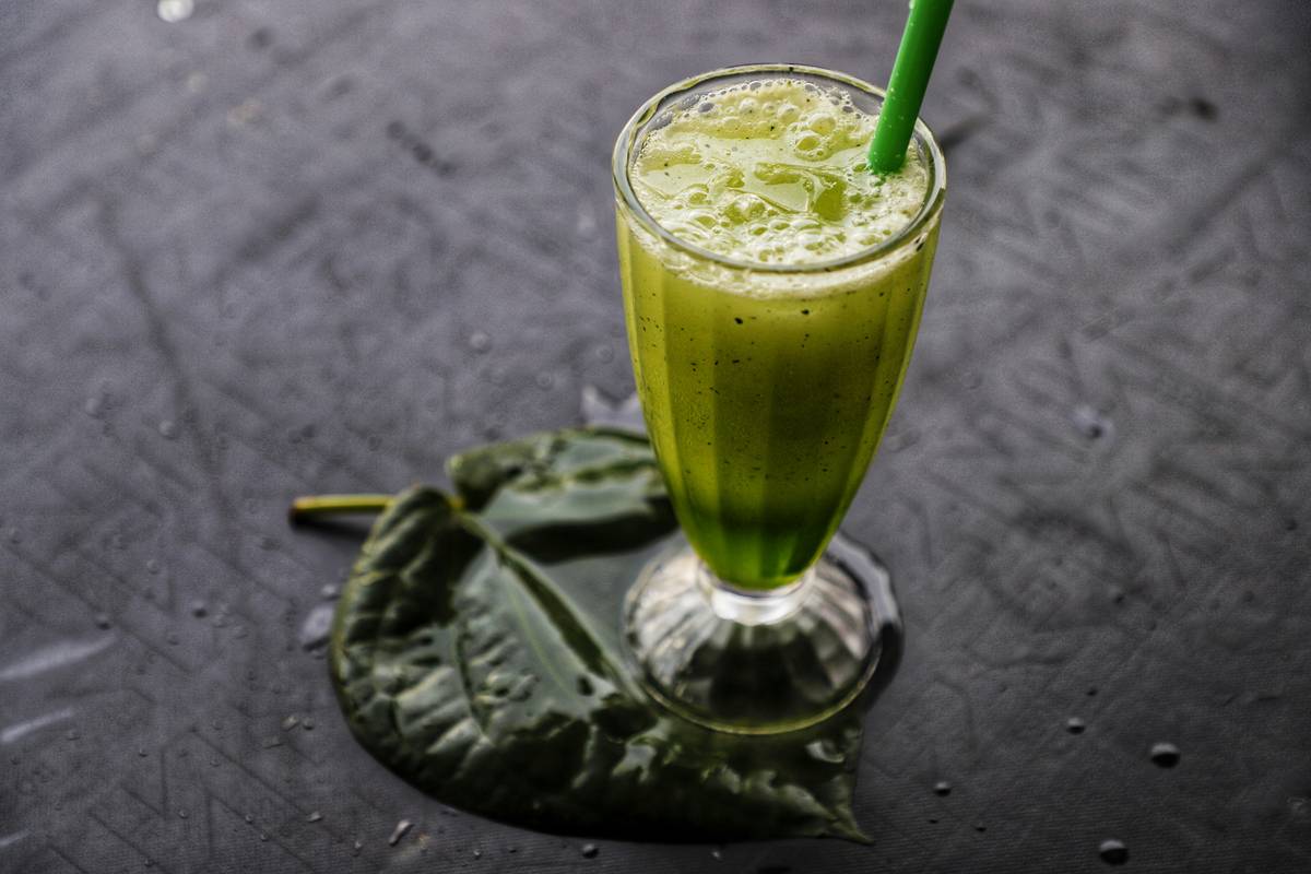 Woman preparing a natural health beverage with spinach, berries, and almond milk in a blender