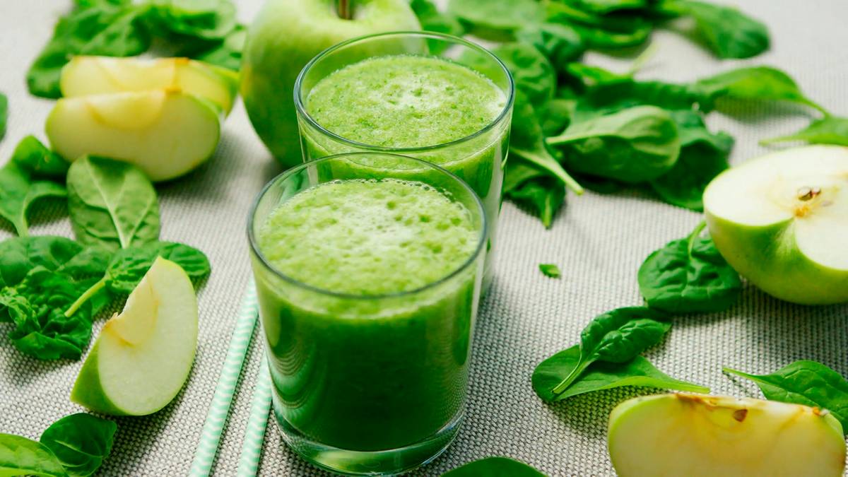organic veggie smoothie formula in a glass with fresh greens and citrus on a wooden table